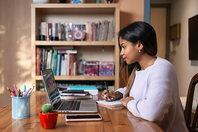 Positive smart young African American female student studying from online webinar or a course at home, video calling and talking