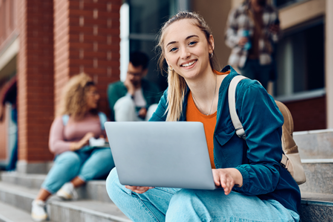 Young woman on her laptop sitting on campus steps outside