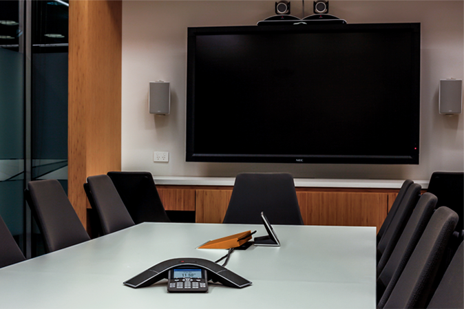 Modern conference room with communication equipment on the table and a tv on the wall